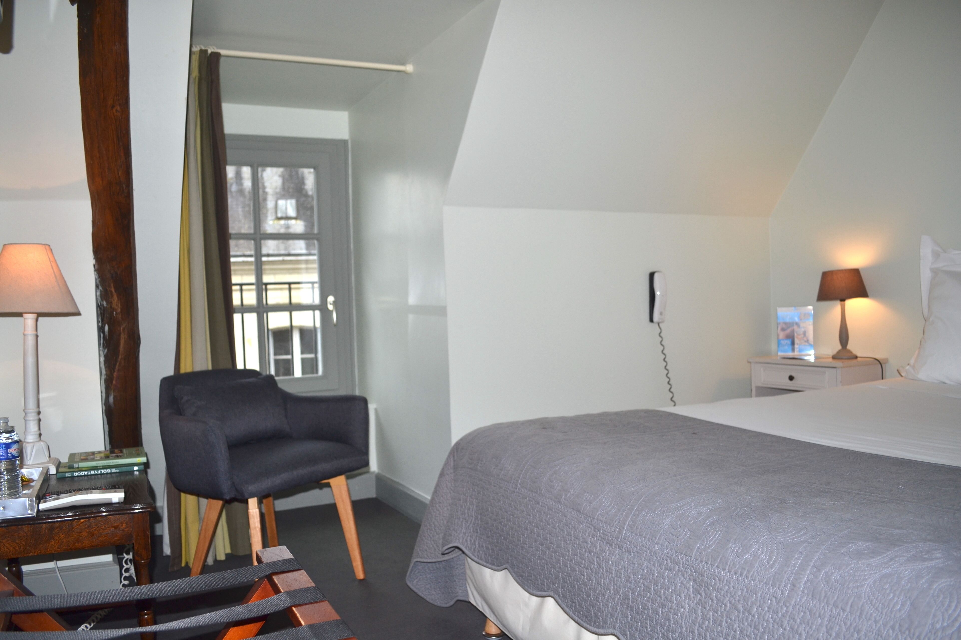 Une chambre à coucher avec un lit, une chaise, une table de chevet et une lampe.