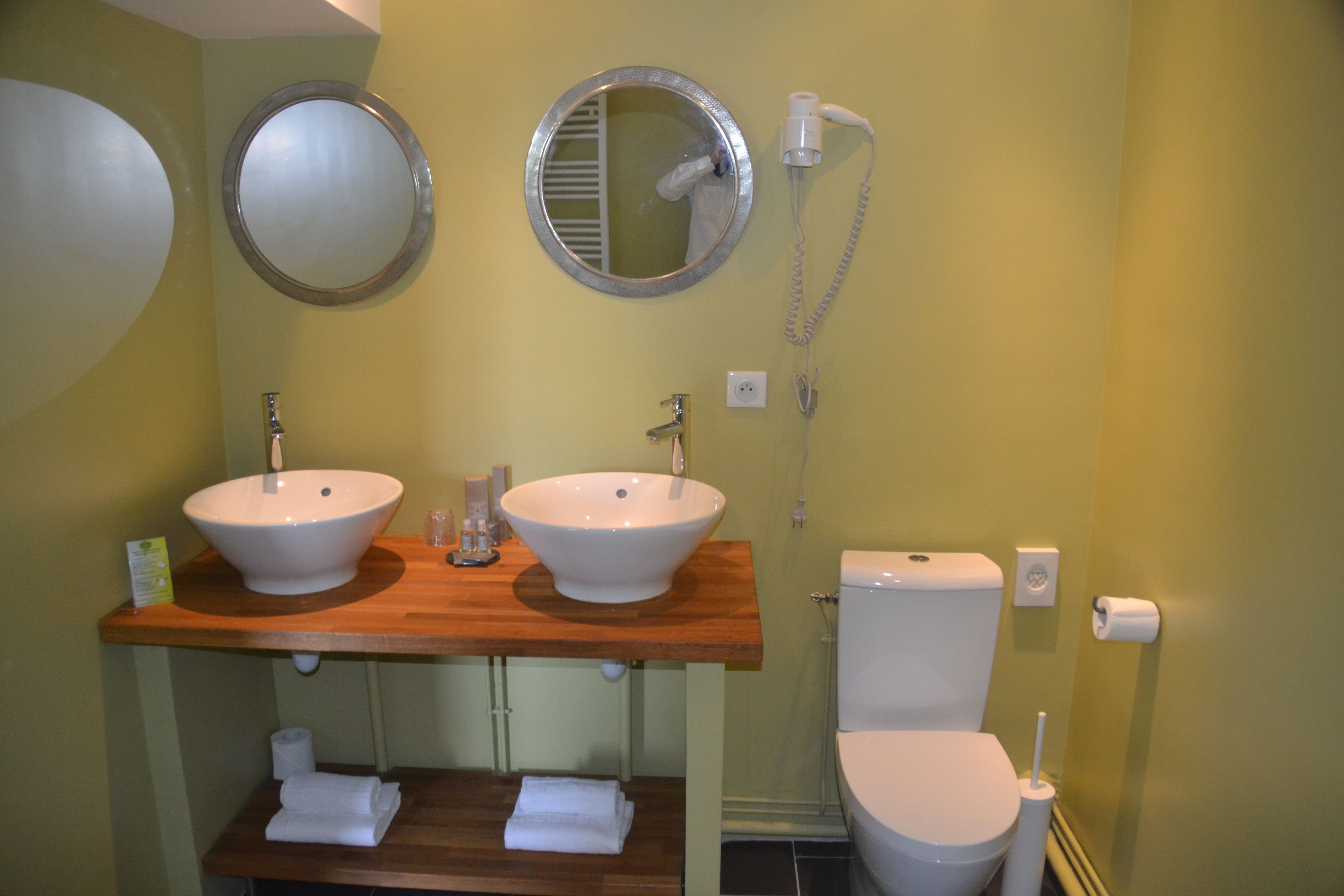 A bathroom with two sinks, a toilet, a mirror, and a hairdryer.