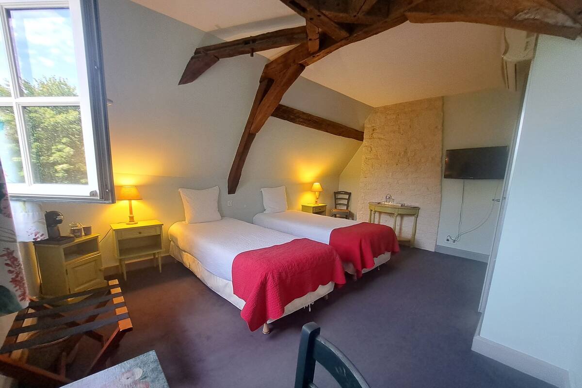 Een slaapkamer met een groot bed, twee nachtkastjes met lampen, een klein tafeltje met een stoel, en een televisie aan de muur.