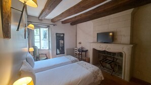 Ein Zimmer mit zwei Betten, einem Kamin, einem Fernseher und einem Fenster mit Blick.