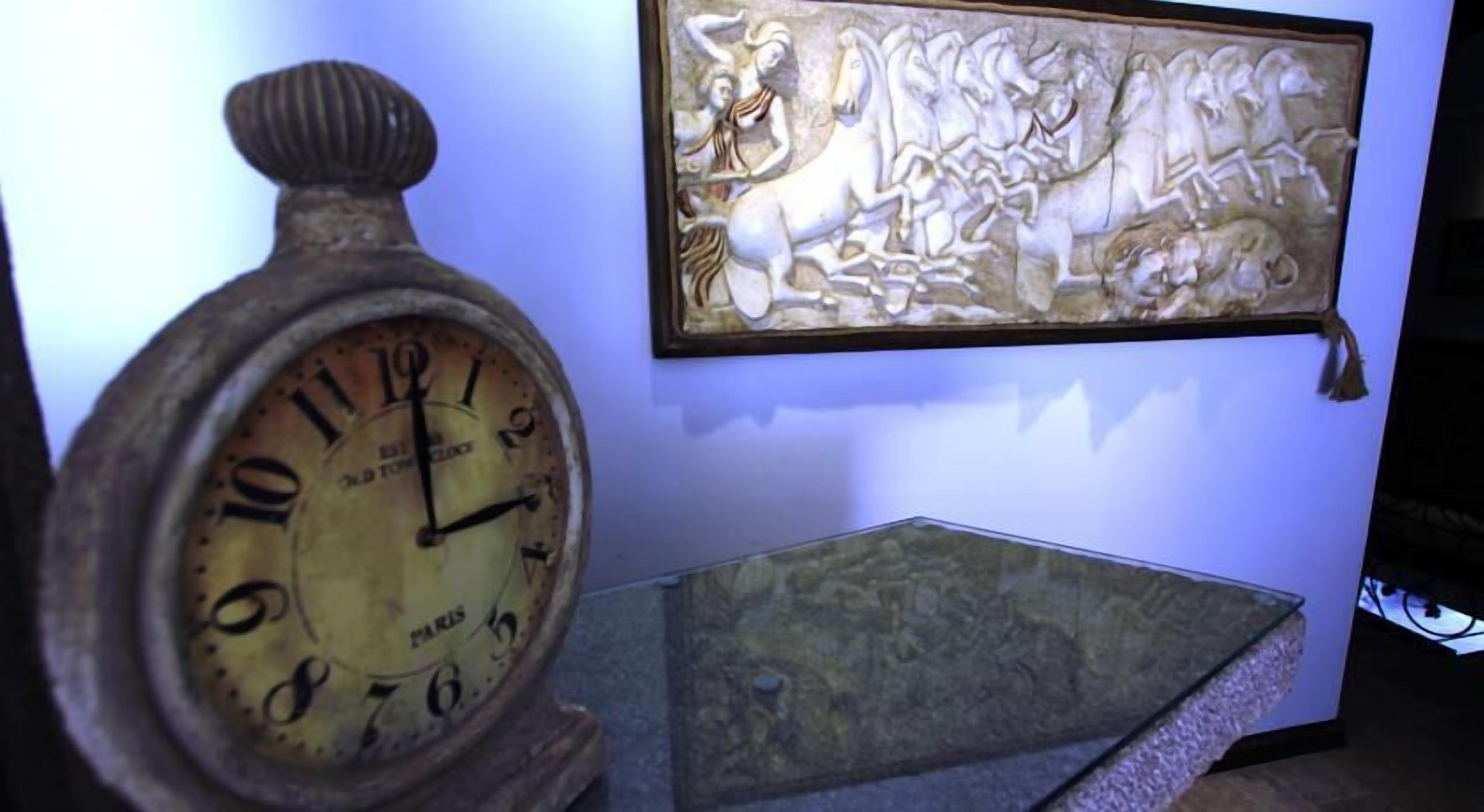 Un reloj de pared con números romanos y un relieve que representa una escena de batalla.