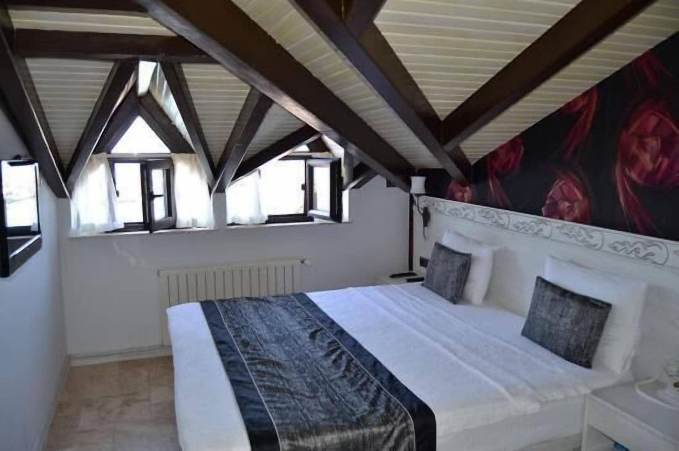 A bedroom with a large bed, a radiator, and a window with curtains.