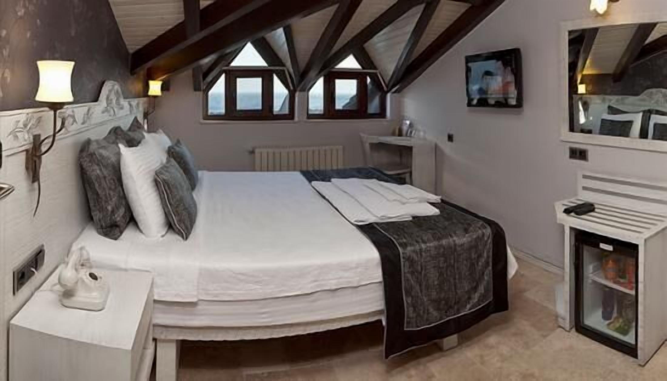 Une chambre à coucher avec un grand lit, une table de chevet, une commode, un miroir et une fenêtre donnant sur un beau paysage.