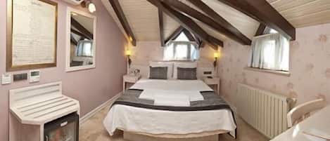 Een slaapkamer met een bed, een bureau, een spiegel en een radiator.
