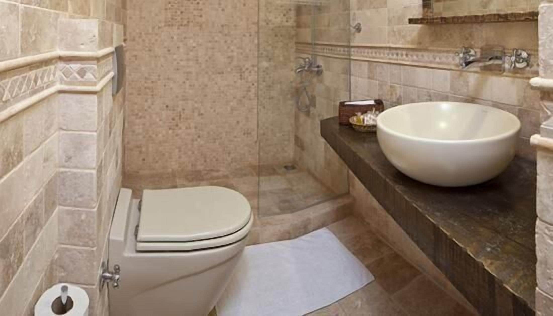 Un baño con inodoro, un lavamanos blanco grande y una zona de ducha.