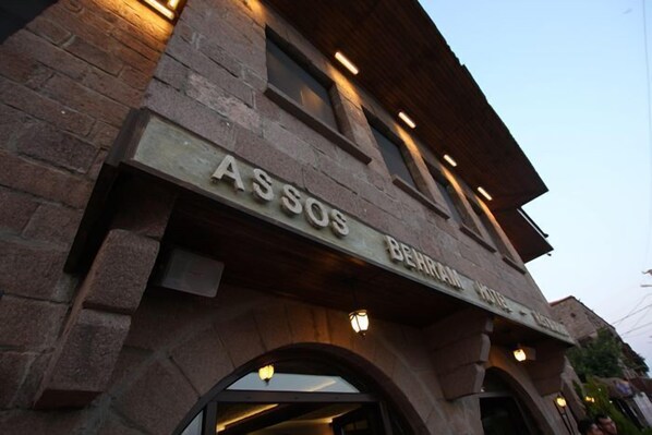 Un edificio de piedra con el cartel "ASSOS BEHRAM HOTEL" que indica un establecimiento hotelero.