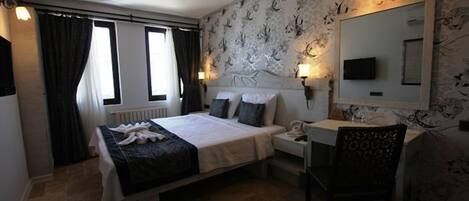 Habitación de hotel con cama, mesita de noche, silla y un espejo grande.