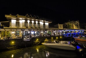 Una propiedad frente al agua con un edificio de piedra, asientos al aire libre y un muelle con barcos.