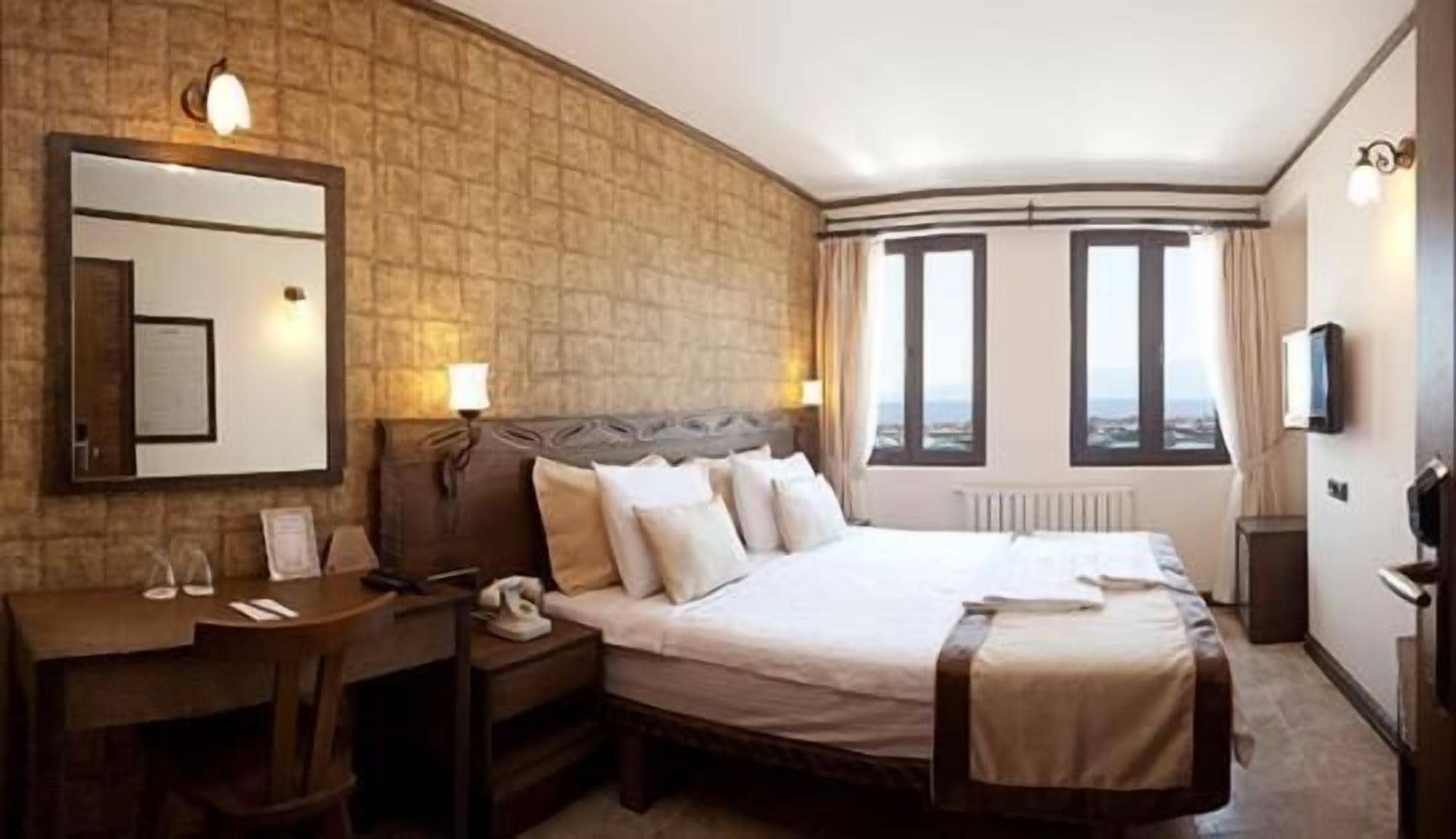 Habitación de hotel con una cama grande, un escritorio, una silla, un teléfono y una televisión.