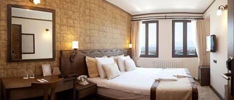 Habitación de hotel con una cama grande, un escritorio, una silla, un teléfono y una televisión.