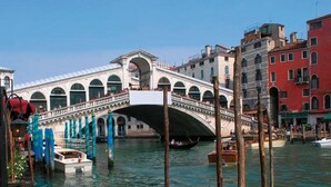 A historic bridge with multiple arches over a canal, surrounded by traditional buildings. - Ca' Rialto House (Venice)