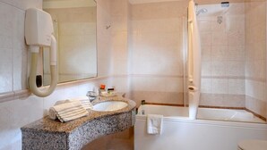 A modern bathroom with a granite countertop sink, a large mirror, a white bathtub, and a handheld showerhead. - Ca' Rialto House (Venice)