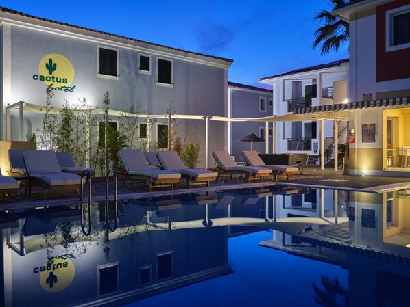 A pool area with lounge chairs and a sign for the Cactus Hotel. - Cactus Hotel (Zakynthos)