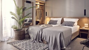 A modern bedroom with two beds, a large mirror, a hanging light, and a potted plant. - Cactus Hotel (Zakynthos)