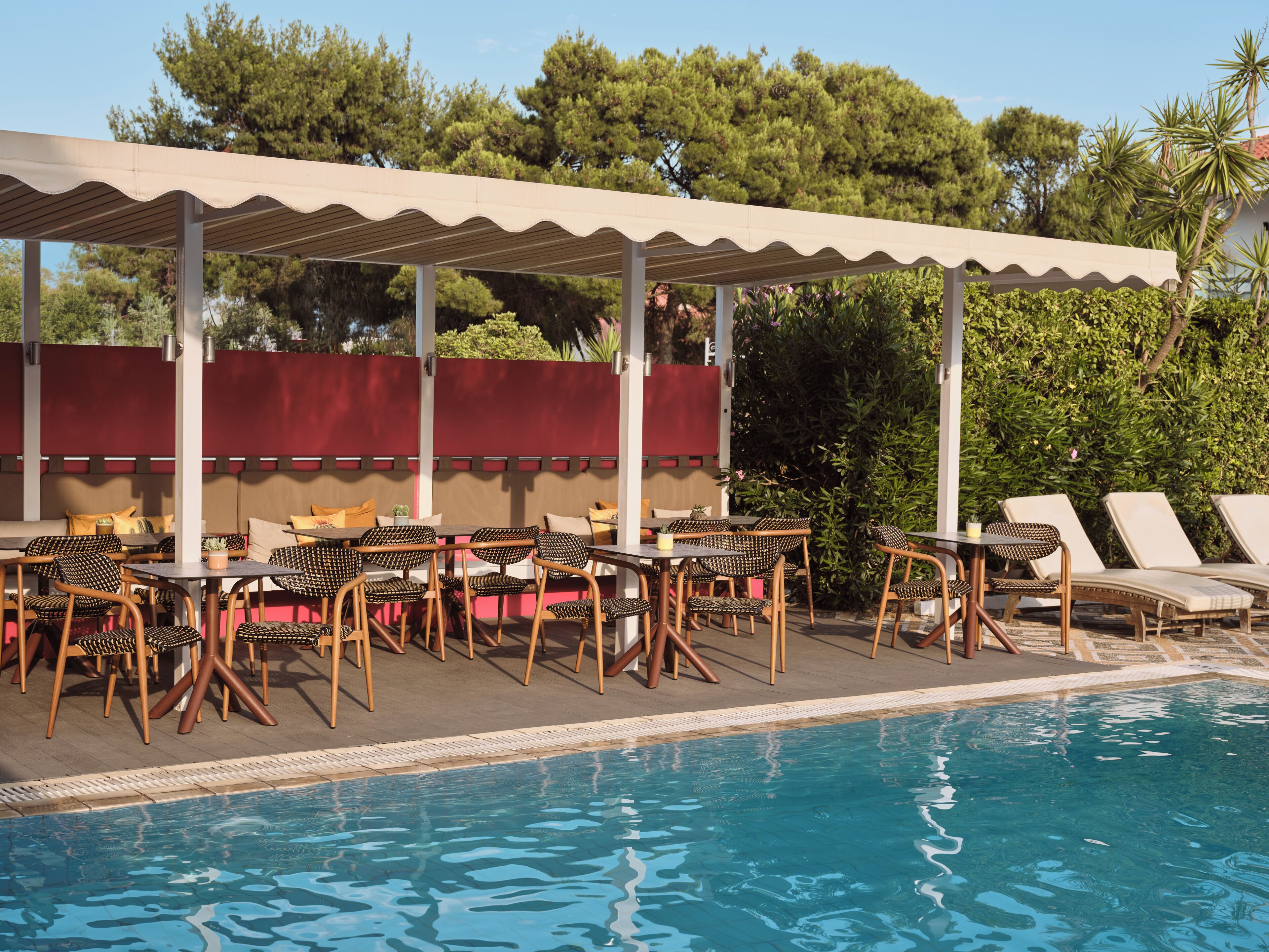 A poolside area with lounge chairs, tables, and a covered seating area.
