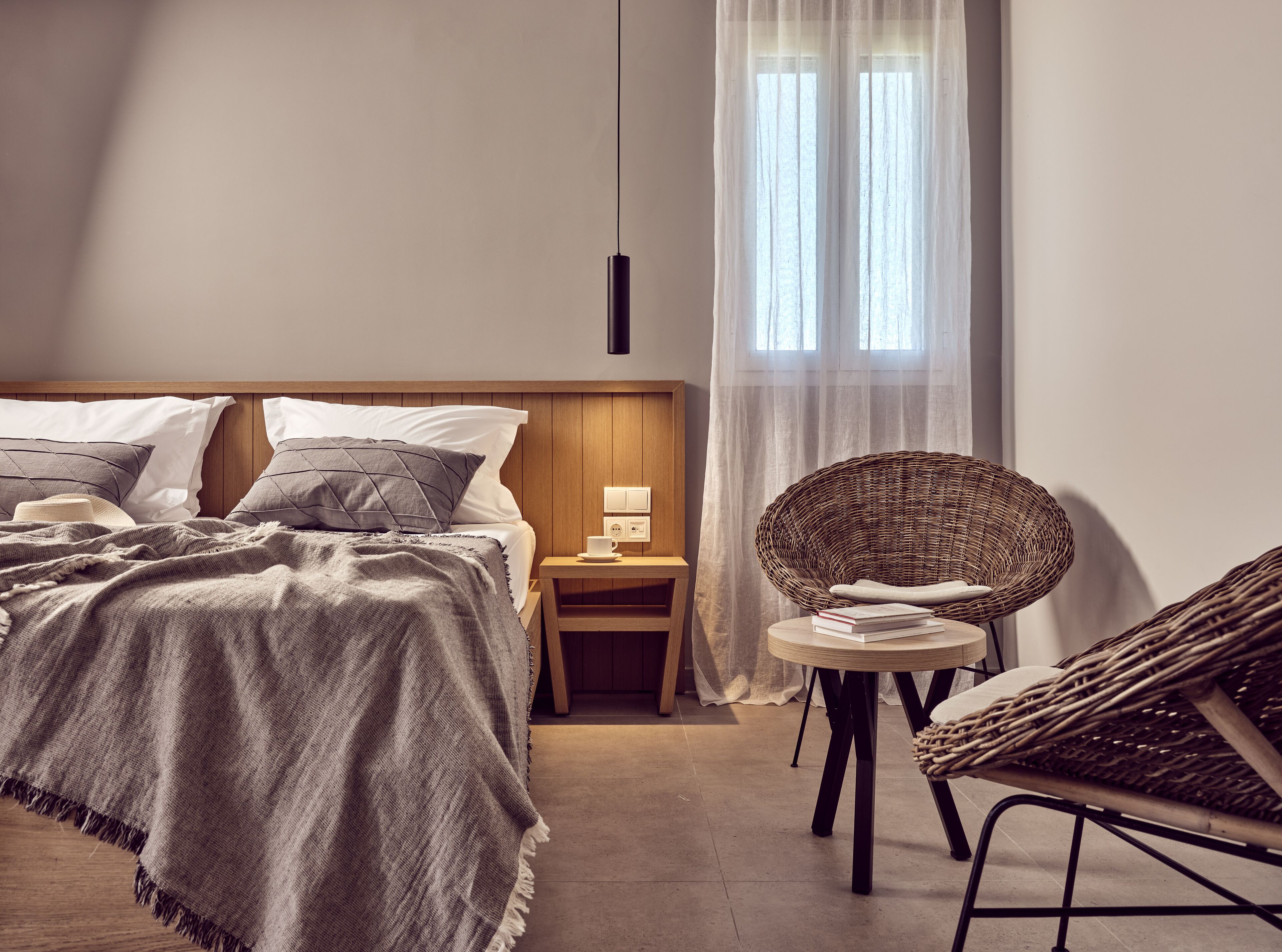 Un dormitorio con cama, mesita de noche y una silla de mimbre.