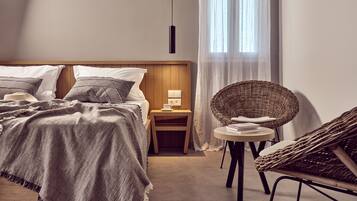 Un dormitorio con cama, mesita de noche y una silla de mimbre.