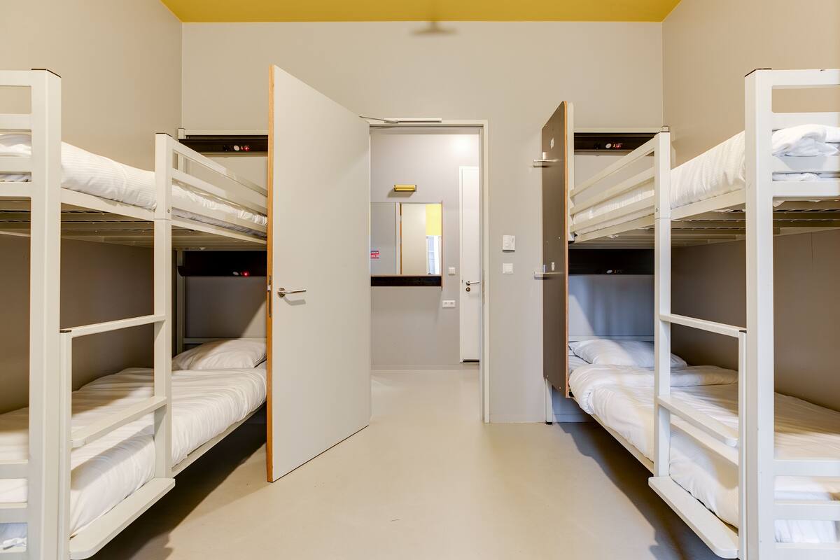 A corridor with bunk beds on either side, leading to a door.