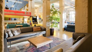 Un amplio salón con sofá, mesa de centro y una planta grande.
