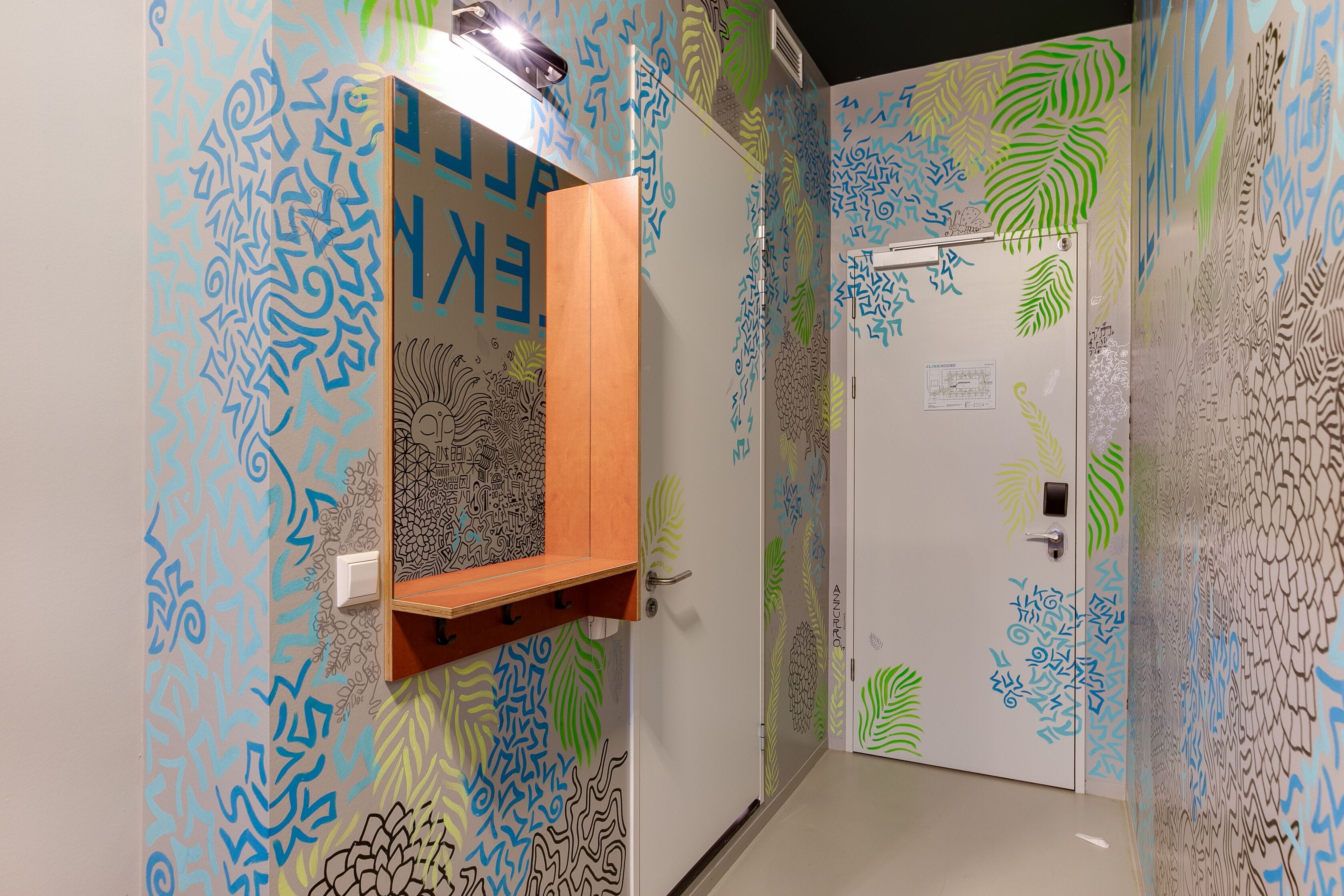 A bathroom with a wooden shelf, patterned walls, and a white door with a fingerprint design.