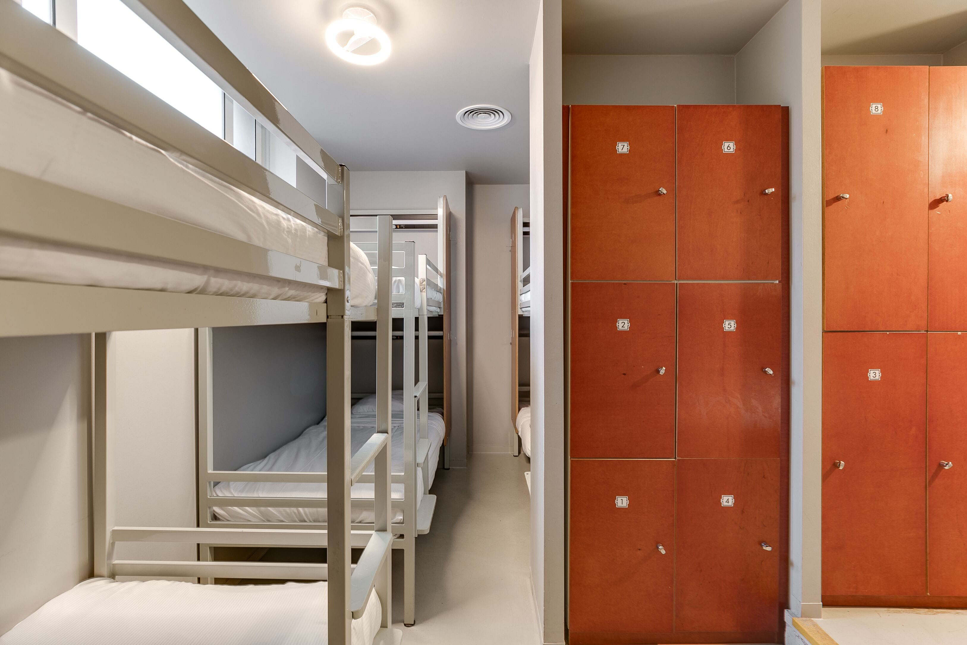 A bunk room with bunk beds and a row of wooden lockers.