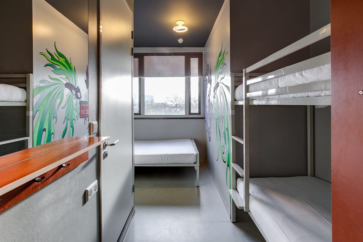 A narrow train compartment with bunk beds, a small window, and a wooden shelf.