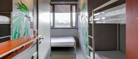 A narrow train compartment with bunk beds, a small window, and a wooden shelf.