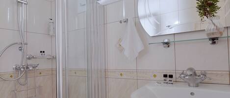 Un baño con cabina de ducha de vidrio, un lavabo blanco y un espejo sobre él.