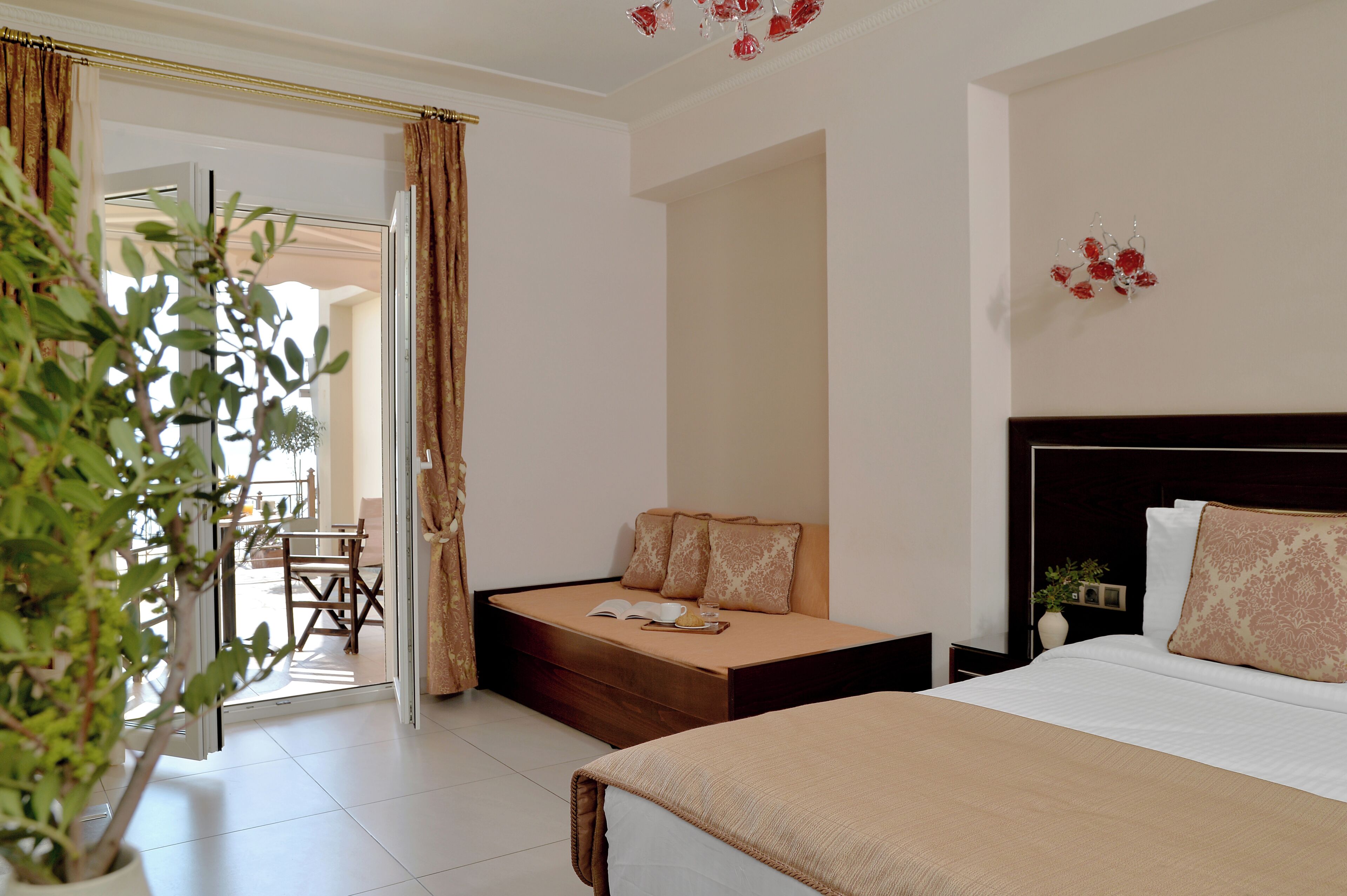 Une chambre d’hôtel comprenant un lit, un canapé-lit, un coin repas et une plante en pot.