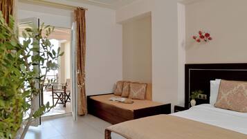Une chambre d’hôtel comprenant un lit, un canapé-lit, un coin repas et une plante en pot.