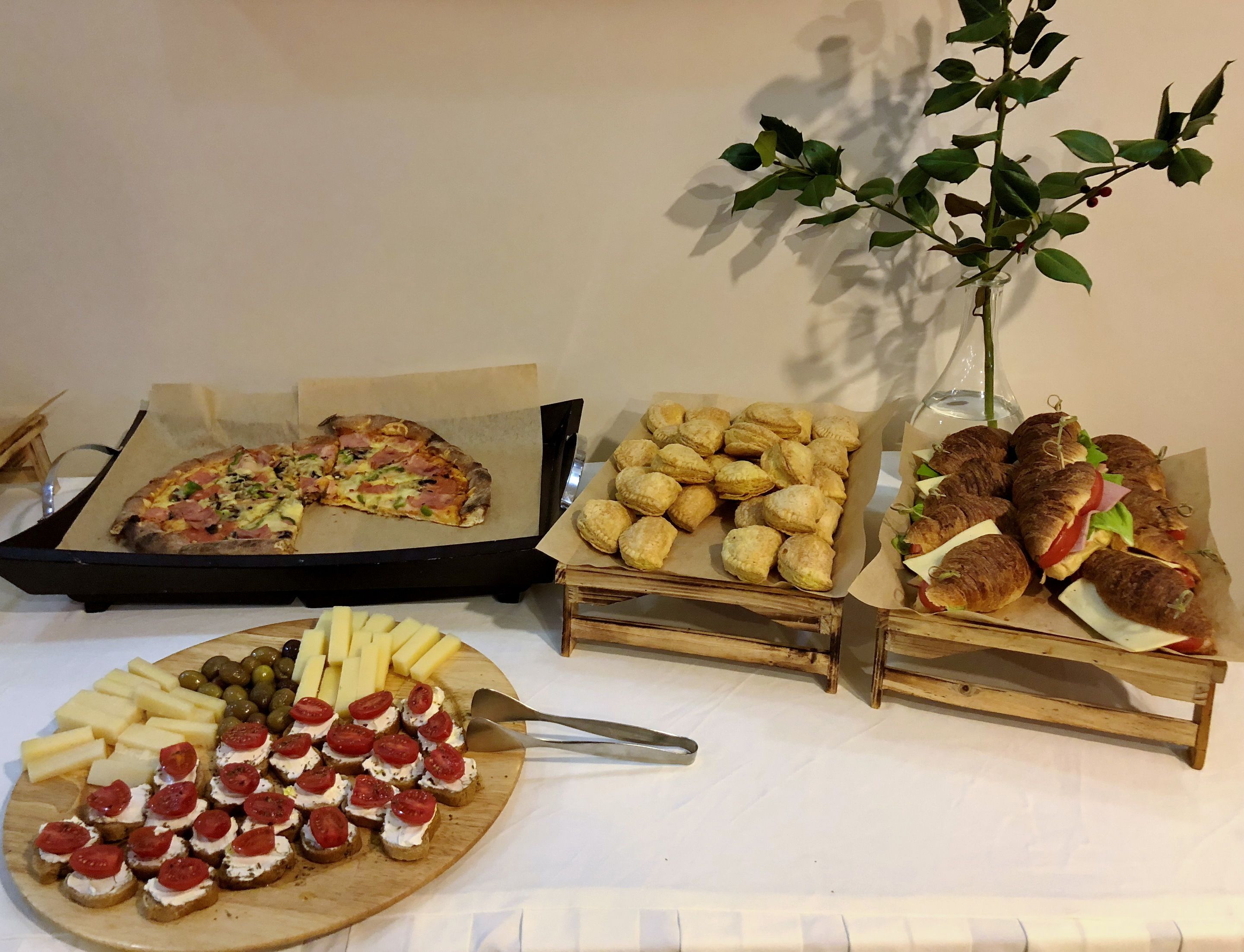 A variety of food items including a pizza, pastries, sandwiches, and appetizers on a table.
