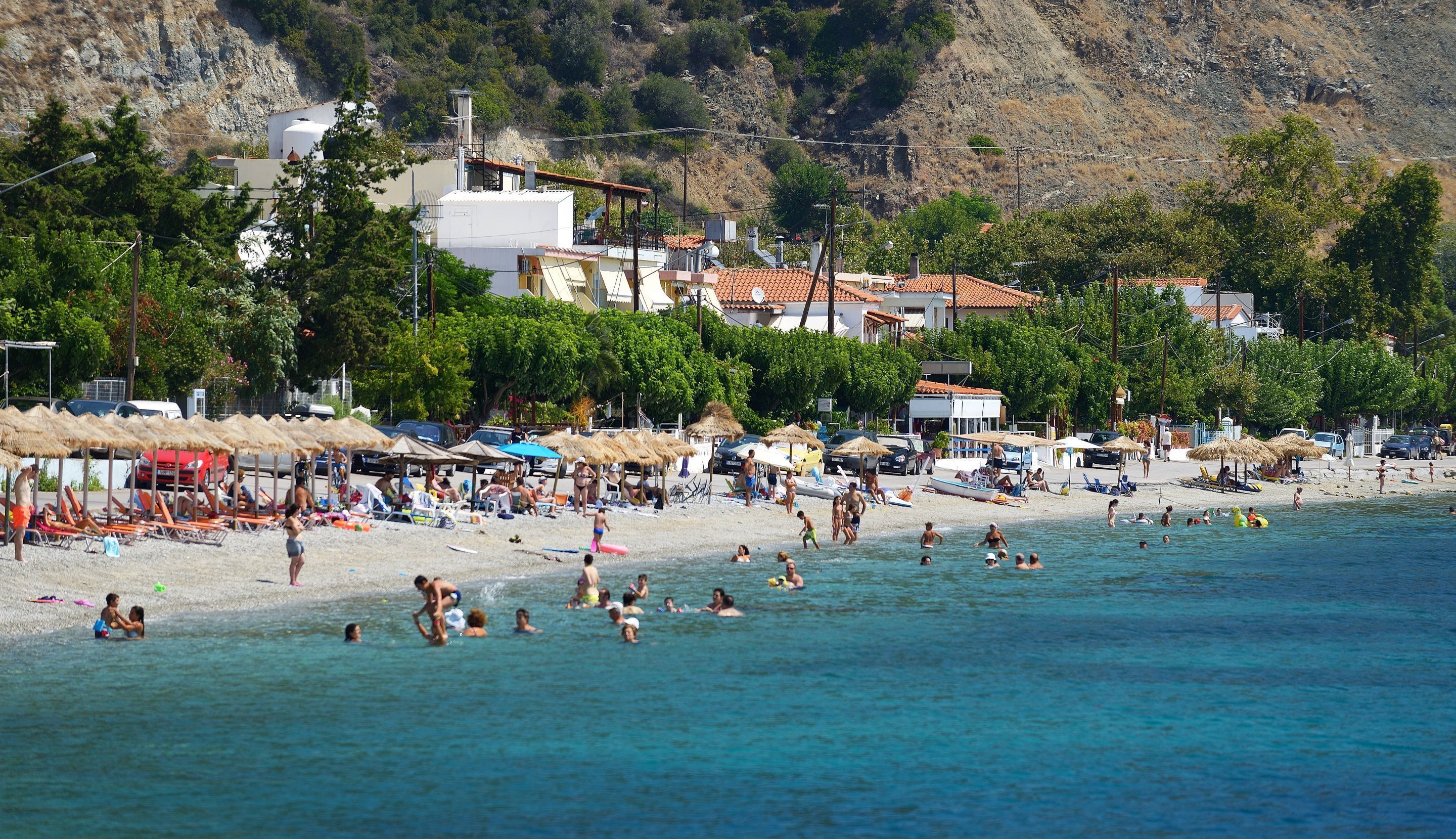 Une plage où l’on peut se baigner et bronzer, avec des parasols et des chaises de plage.