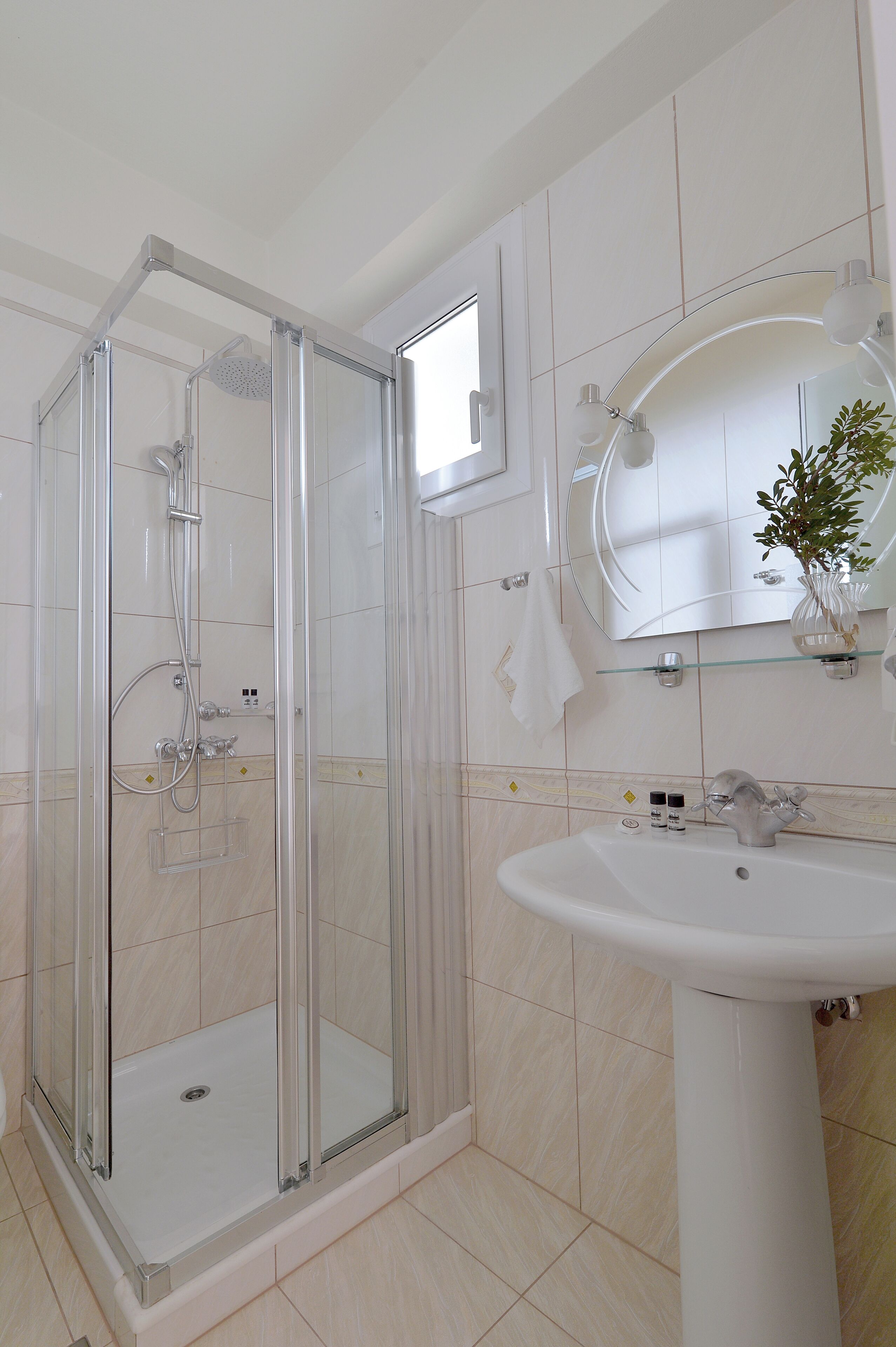Baño con ducha de vidrio, lavamanos y espejo.