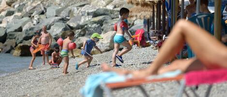A beach with people, including children playing and adults relaxing.
