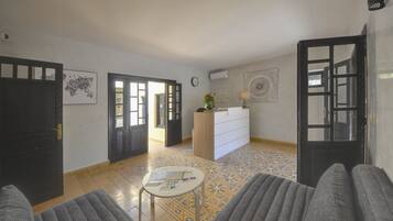 A living room with a sofa, a coffee table, a TV, and a door leading to another room.