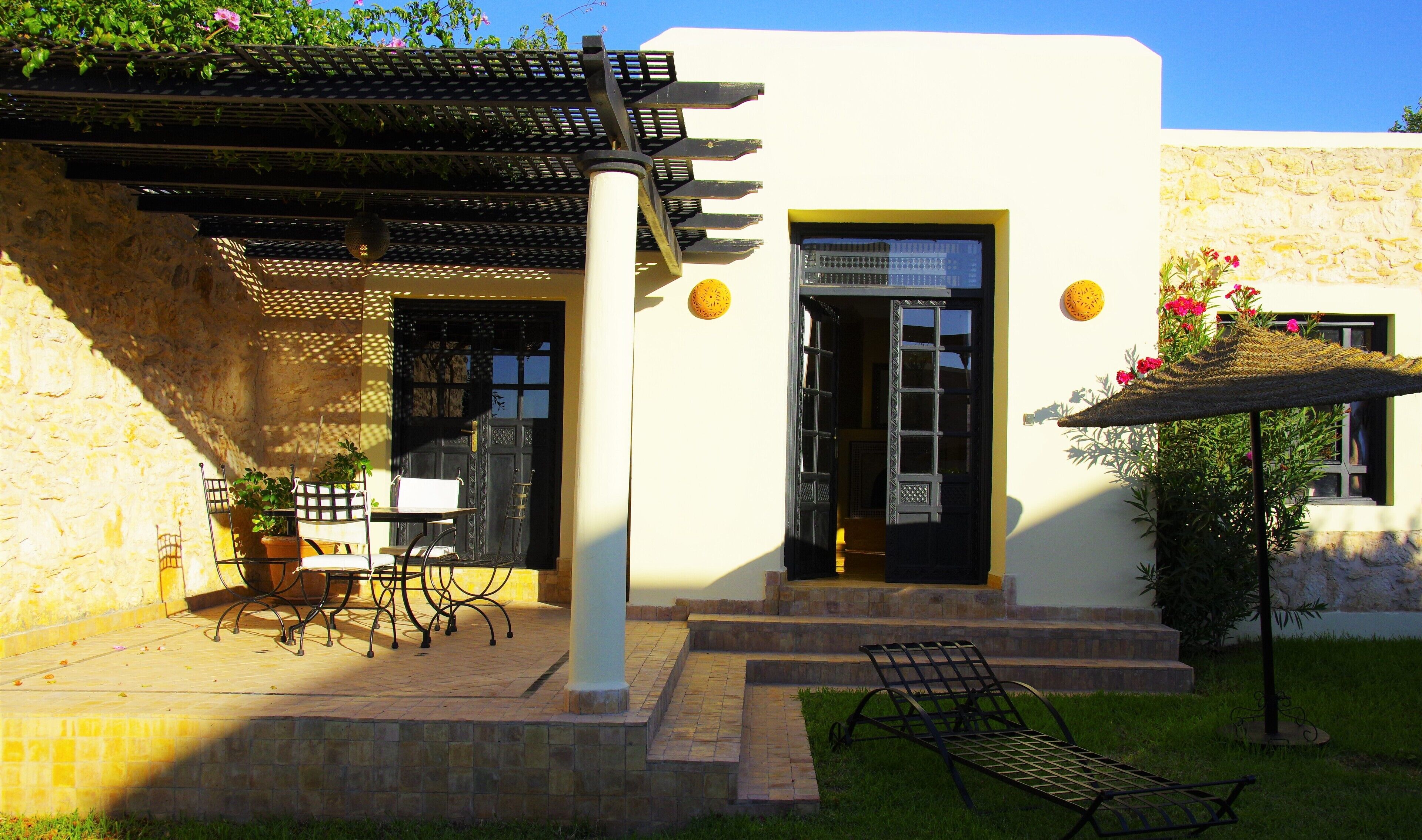 Un edificio con fachada de piedra, una puerta negra y un pequeño patio con una mesa y sillas.