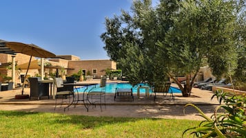 Una piscina al aire libre, sombrillas, sillones reclinables de piscina