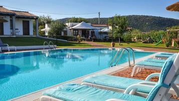 Relax by the serene pool surrounded by lush greenery and a mountain view.
