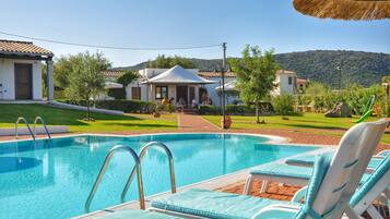 Una piscina con lettini, una zona relax coperta e vista sul paesaggio circostante.
