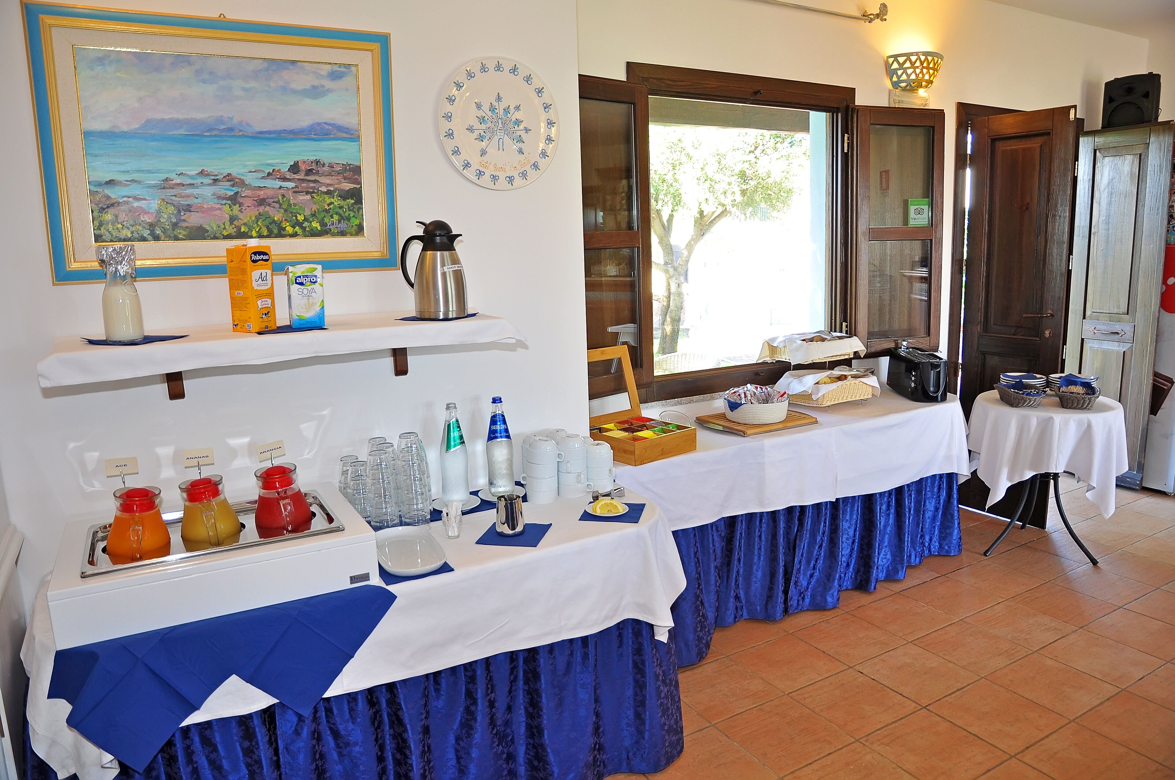 Un buffet de petit-déjeuner proposant une variété de plats et de boissons, un tableau accroché au mur et une vue sur l’extérieur.