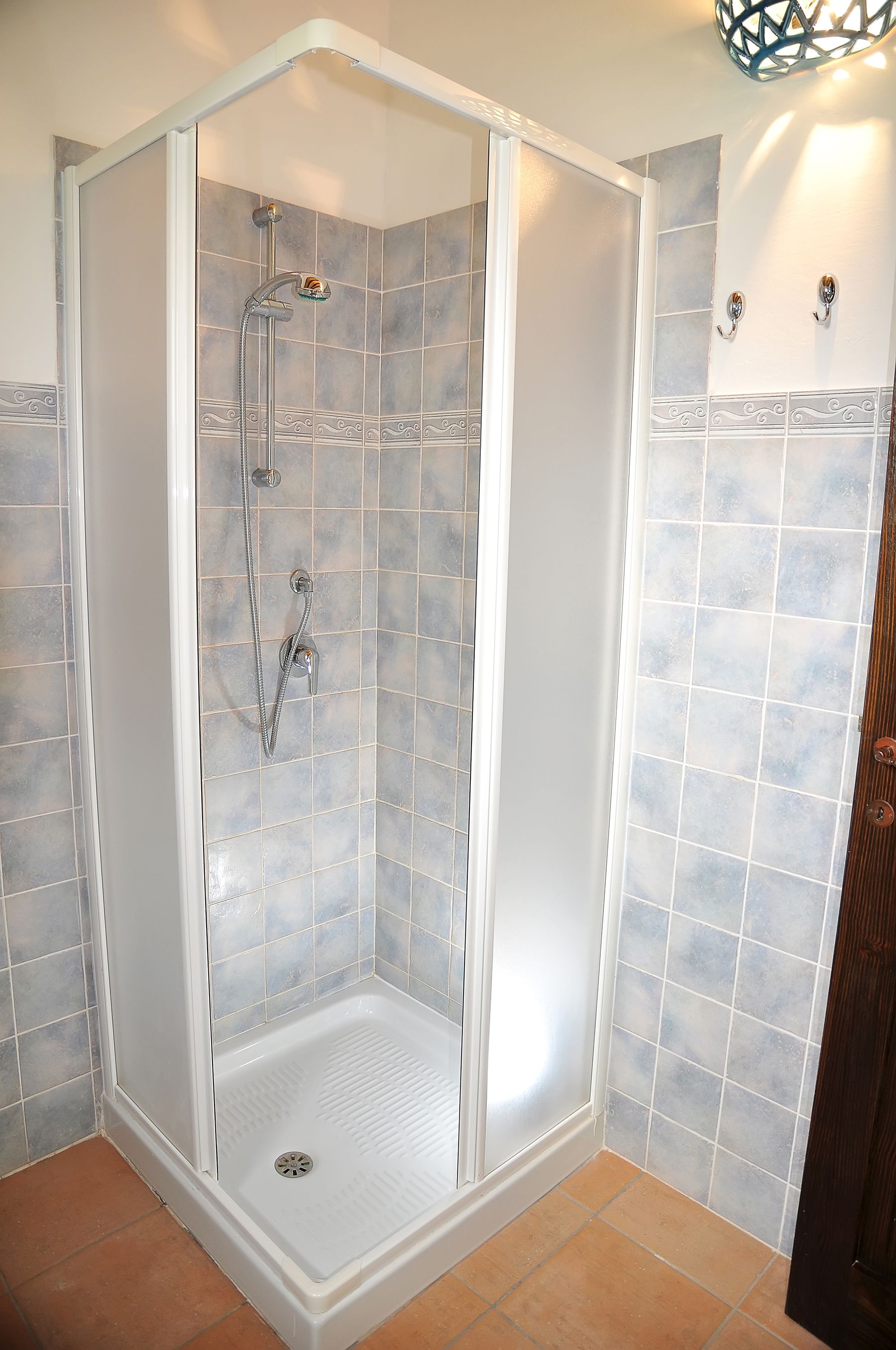 A shower enclosure with a glass door, tiled walls, and a showerhead.