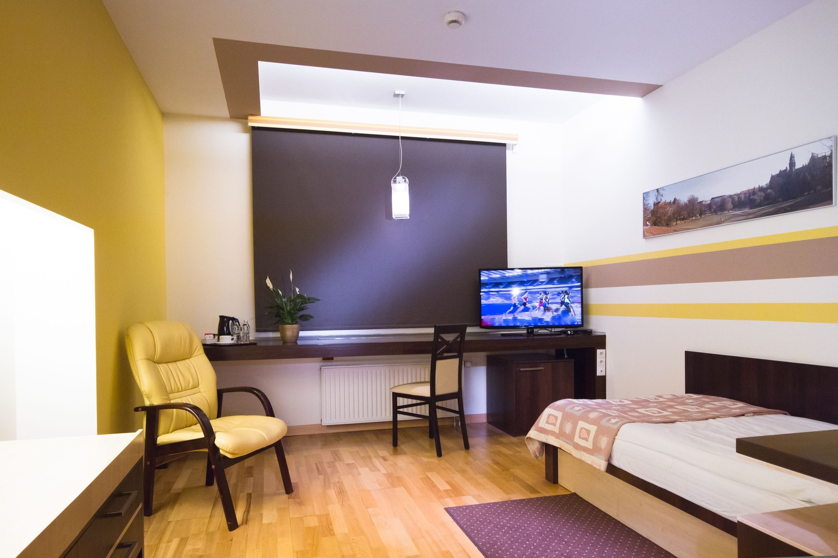 Una camera d'hotel con un letto, una scrivania con una sedia, una televisione e una finestra con persiane.