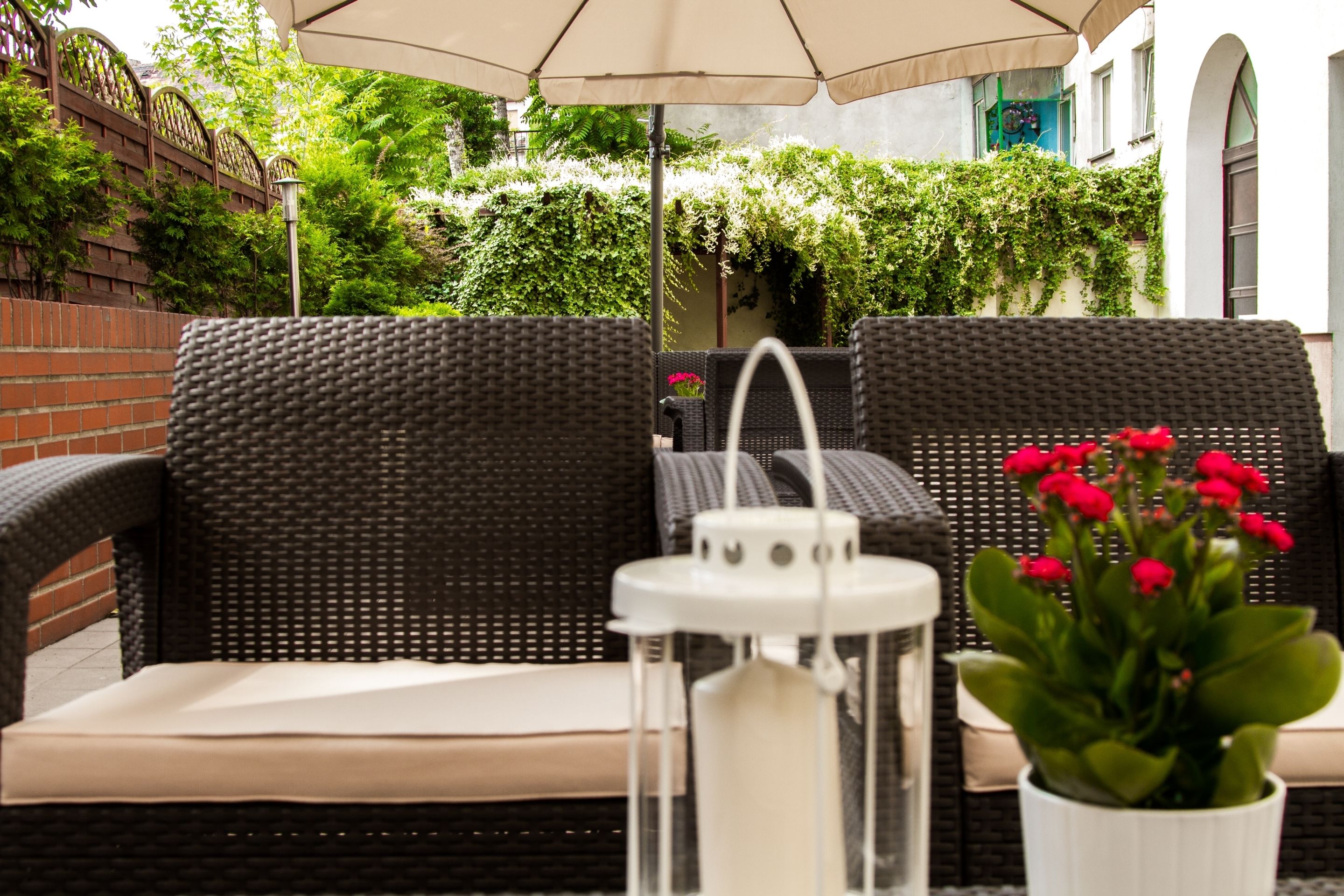 A wicker outdoor seating area with a white lantern and a potted plant.