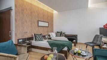 Una habitación de hotel moderna con una cama, mesitas de noche, un escritorio y un área de descanso.