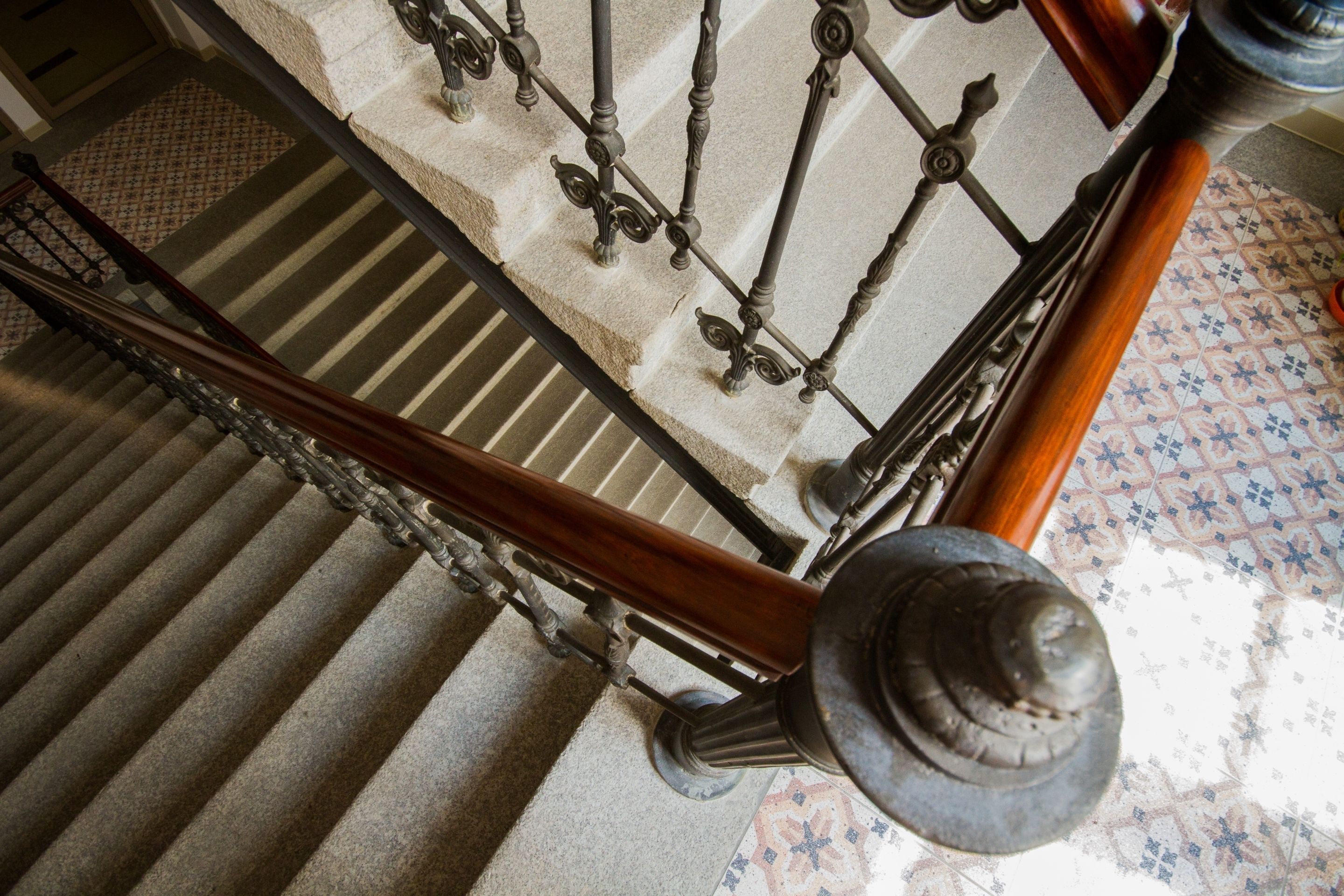 A staircase with a wooden handrail and metal balusters, leading to a carpeted landing area.