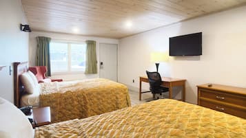 A hotel room with two beds, a desk with a chair, a TV, and a window with curtains.