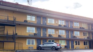 A multi-story building with balconies, air conditioning units, and a parked car.