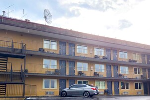 A multi-story building with balconies, air conditioning units, and a parked car.