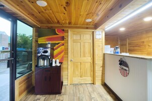 Un interior de madera con una recepción, una máquina de café y una puerta.