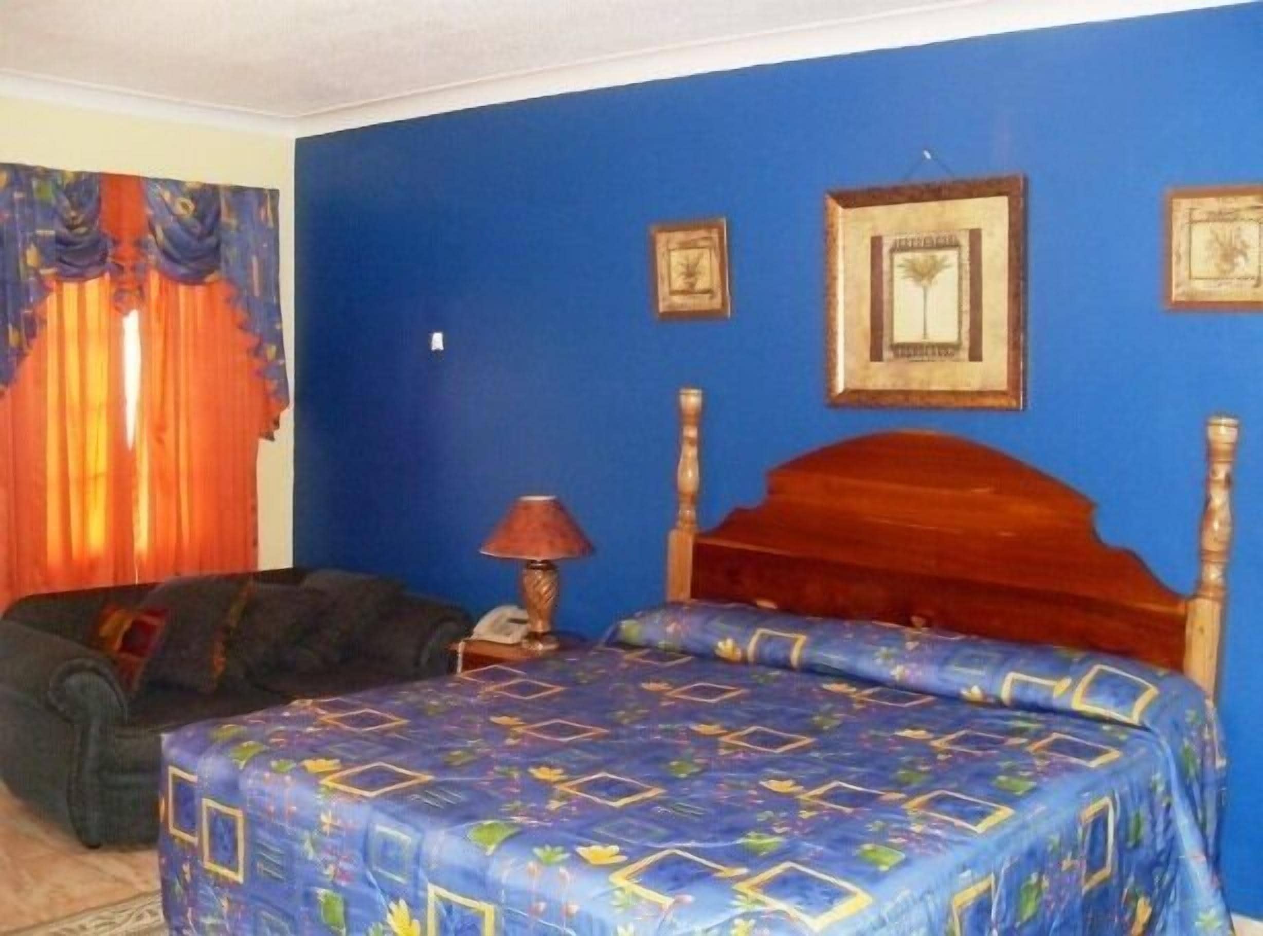 Een slaapkamer met een blauwe wand, een houten bedframe en een bed met een dessin.